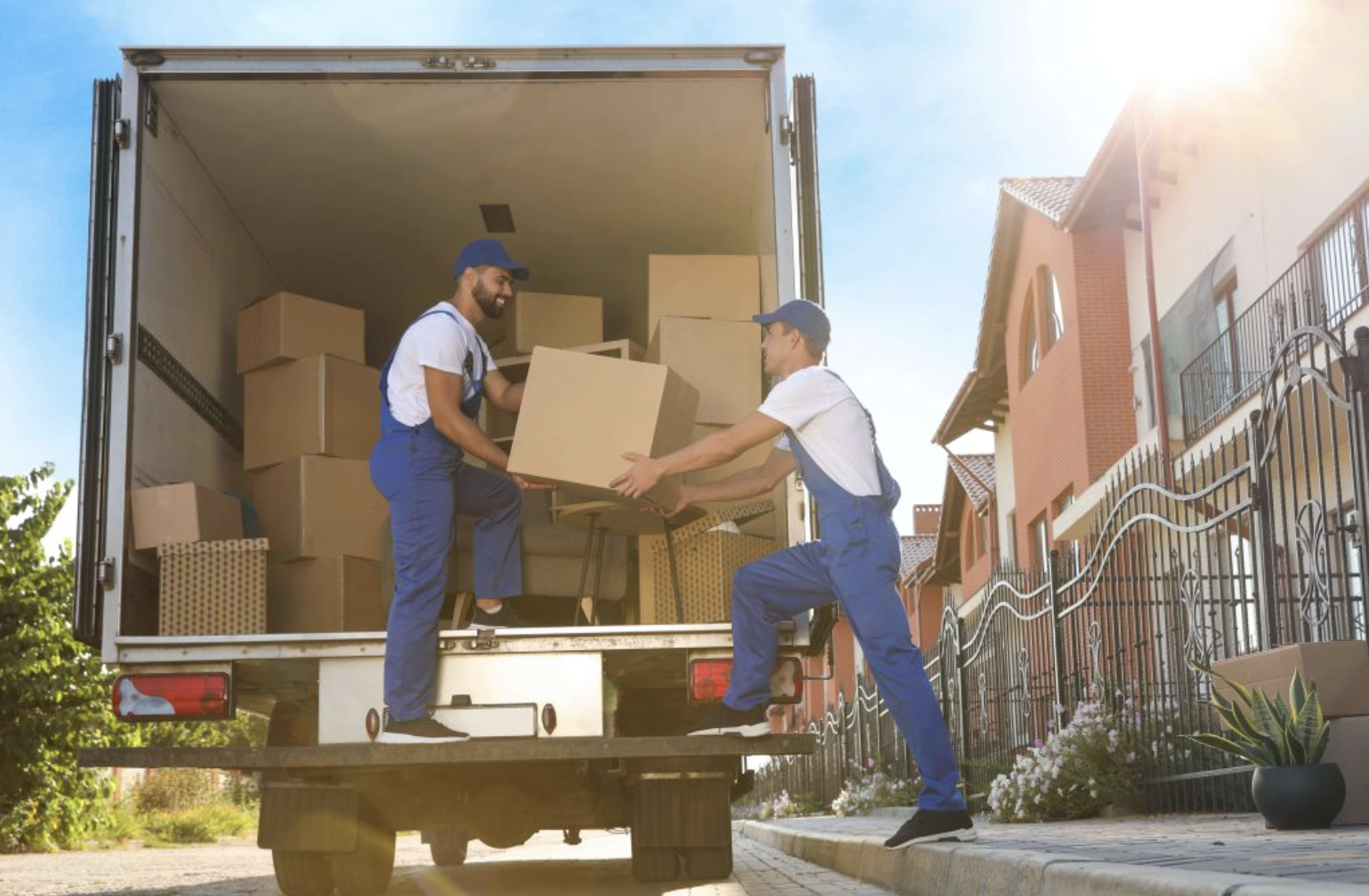 Professional movers in blue uniforms carefully loading boxes into moving truck